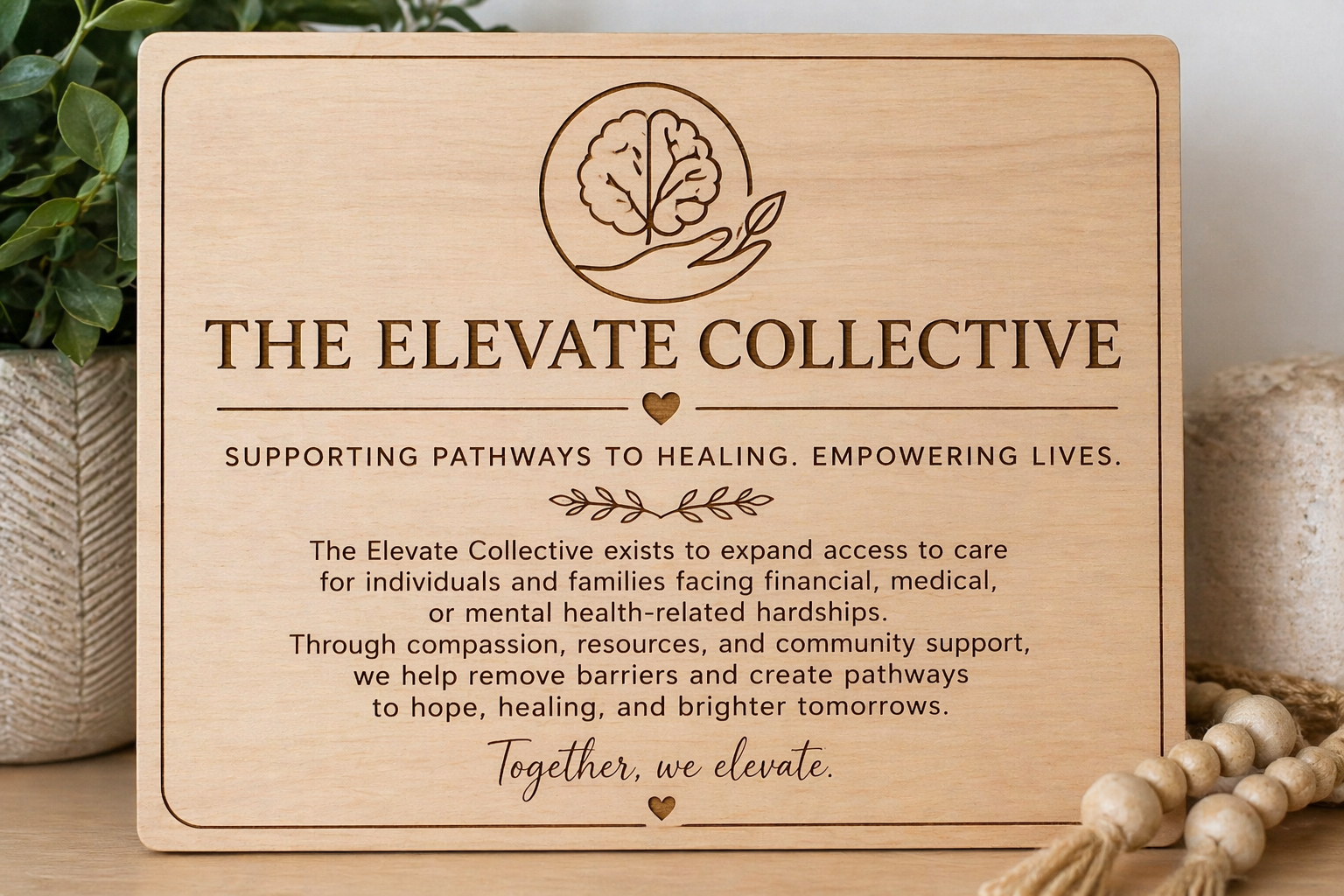 Wooden plaque with 'The Elevate Collective' branding and mission statement on a wooden surface.